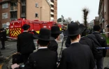 Des habitants sont rassemblés près d'un camion de pompiers après une attaque "antisémite" à Londres ayant visé quatre ambulances gérées par une association juive, le 23 mars 2026