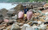 Un homme ramasse des détritus en plastique pendant une opération de collecte de déchets sur la côte près de Clear Water Bay à Hong Kong, le 9 novembre 2023