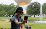 Une femme prend un selfie devant la vasque olympique aux allures de montgolfière posée dans le jardin des Tuileries, le 27 juillet 2024 à Paris