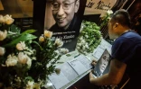 Un homme écrit un message et tient un portrait du dissident chinois Liu Xiaobo après le décès de celui-ci, devant le bureau de liaison chinois à Hong-Kong