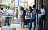 Des membres de le Croix-Rouge monégasque avec des migrants le 14 juin 2018 à la gare de Vintimille, dans le nord de l'Italie, à proximité de la frontière avec la France