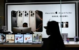 Une femme passe devant un magasin d'électronique dans un centre commercial à Pékin le 13 avril 2025