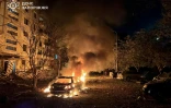 Photo prise et diffusée par les services d'urgence ukrainiens, le 5 octobre 2025, montrant une voiture en feu dans la cour d'un immeuble résidentiel après une attaque aérienne russe à Zaporijjia, en Ukraine