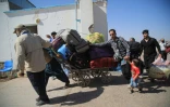 Des réfugiés afghans transportent leurs biens après avoir traversé depuis l'Iran la frontière à Islam Qala, dans la province d'Hérat, le 24 juillet 2025 en Afghanistan