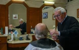 Le coiffeur Roger Amilhastre (D), âgé de 90 ans, dans son salon à Saint-Girons, en Ariège, le 16 avril 2024