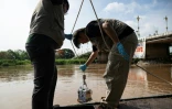 Le chercheur Wan Wiriya (à gauche) et un de ses collègues prélèvent des sédiments de la rivière Kok, le 5 juin 2026 à Chiang Rai