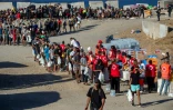 Des bénévoles de la Croix-Rouge distribuent de la nourriture aux migrants restés à Ceuta, sur une plage de l'enclave espagnole au Maroc, le 22 août 2026