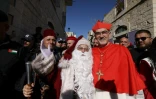 Le patriarche latin de Jérusalem, le cardinal Pierbattista Pizzaballa, pose pour une photo avec un homme habillé en Père Noël avant son arrivée à l'église de la Nativité, à Bethléem, en Cisjordanie occupée, le 24 décembre 2024