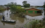 Un homme dans une barque se tient devant une maison inondée à Canoas, dans le sud du Brésil, le 13 mai 2024