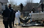 Des experts de l'Institut de Recherches criminelles de la Gendarmerie nationale (IRCGN) sur le site d'une fosse commune pendant l'exhumation de corps, le 14 avril 2022 Ă Boutcha, au nord-ouest de Kiev, en Ukraine