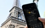 Une personne près de la Tour Eiffel tient son smartphone indiquant la température de 42 degrés Celsius, le 25 juillet 2019 à Paris