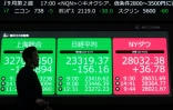 Un piéton marche devant un panneau électronique affichant les valeurs de la Bourse de Tokyo et d'autres marchés de Tokyo, à Tokyo, le 17 septembre 2020