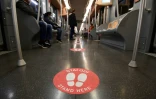 Une rame du mĂ©tro de Milan oĂč les passagers sont invitĂ©s Ă respecter les distances de sĂ©curitĂ©, avec au sol un autocollant portant l'inscription "Mettez-vous ici", le 28 avril 2020
