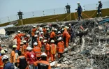 Les secouristes birmans et chinois transportent le corps d'une victime après l'effondrement d'un immeuble lié au séisme en Birmanie, à Mandalay, le 2 avril 2025