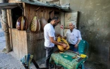 Le luthier palestinien Souhail Abou Chawich reçoit un ouds à réparer dans son atelier du camp de réfugiés de Nousseirat, dans le centre de la bande de Gaza, le 23 juin 2026