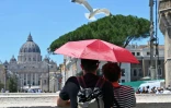 Un couple se protège du soleil avec un parapluie en admirant le Vatican depuis le pont Sant'Angelo à Rome, le 23 mai 2026 en Italie