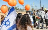 Des Israéliens portant des ballons orange attendent le convoi funéraire de la famille Bibas au kibboutz Nir Oz, le 26 février 2025