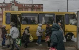 Des passagers à une station de bus où des filets antidrones ont été disposés le long de la route, le 30 octobre 2026 à Kherson, dans le sud de l'Ukraine 

