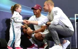 Les pilotes britanniques Lewis Hamilton (c) et Valtteri Bodas (d) parlent avec une jeune supportrice en marge du GP de Singapour, le 13 mai 2018 à Singapour