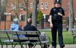 Un policier demande à un couple de ne pas rester assis sur un banc du parc Royal Pump Room Gardens à Leamington Spa, dans le centre de l'Angleterre, le 9 avril 2020 