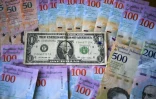 Des bolivars, la monnaie vénézuélienne, et un billet d'un dollar, à Caracas le 28 janvier 2019