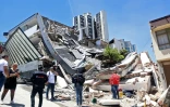 Des personnes se tiennent près d'un amas de débris après un puissant tremblement de terre à Manizales en Colombie, le 10 août 2026