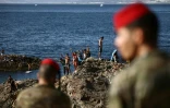 Des militaires espagnols regardent un groupe de jeunes gens sur des rochers à proximité du poste-frontière de l'enclave espagnole de Ceuta, le 2 août 2026 à Ceuta
