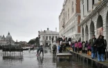 Des piétons marchent sur une passerelle au dessus d'un quai inondé, à Venise le 13 novembre 2019