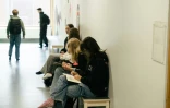 Des élèves assis sur un banc dans un couloir pendant une pause entre les cours au  collège Kungsvägens skola, le 21 août 2025 à Sipoo, en Finlande