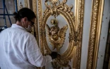 Un employé du Chateau de Versailles nettoie une porte le 17 mai 2021, avant son ouverture le 19 mai, après l'allègement en France des restrictions sanitaire dues à l'épidémie de Covid-19.