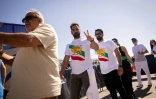 Des supporters iraniens font la queue pour rentrer dans le SoFi Stadium, près de Los Angeles, avec le drapeau utilisé par l'Iran avant la révolution islamique, le 15 juin 2026