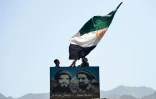 Des Afghans agitent un drapeau afghan au-dessus du portrait du commandant Massoud, dans la vallée du Panchir, le 23 août 2021