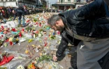 Un homme dépose des fleurs devant un mémorial improvisé place de la Bourse à Bruxelles lors de la marche pacifiste contre le terrorisme le 17 avril 2016