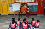 Des élèves assistent à un cours donné à "l'école du feu rouge", qui accueille des enfants défavorisés dans des conteneurs aménagés en salles de cours sous un pont autoroutier, le 18 mai 2026 à Bombay