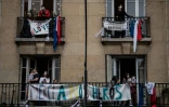 Des personnes applaudissent les personnels soignants à 20h00 aux fenêtres d'un immeuble de Saint-Mandé, le 4 mai 2020 près de Paris