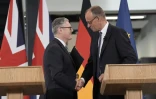 Le Premier ministre britannique Keir Starmer (g) et le chancelier allemand Friedrich Merz se serrent la main après avoir prononcé un discours lors de leur visite de l'usine Airbus à Stevenage, dans le sud de l'Angleterre, le 17 juillet 2025