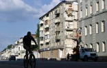 Un homme circule en vélo devant des immeubles détruits dans le centre de Kharkiv, le 27 juillet 2022

