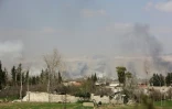 Photo prise depuis les positions des forces du régime syrien montrant de la fumée qui s'élève au-dessus de la ville de Jisrine, dans l'enclave rebelle assiégée de la Ghouta orientale, le 11 mars 2018