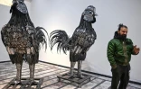 Le sculpteur Ehtisham Jadoon à côté de sculptures de coqs fabriquées à partir de ferraille, dans son atelier situé à la périphérie d'Islamabad, le 29 décembre 2025 au Pakistan