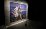 Une visiteuse admire un rideau de scène créé pour le "Train bleu" des Ballets russes, inspiré d'un tableau de Pablo Picasso, exposé à la Storehouse du Victoria et Albert Museum, dans l'est de Londres, le 12 juin 2025