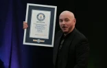 Le rappeur américain Pitbull pose avec son diplôme du Guinness des records grâce à un rassemblement de 22.141 fans portant de faux crânes chauves, le 10 juillet 2026 à Londres