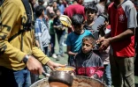 Des Palestiniens font la queue pour une distribution de nourriture dans le camp de réfugiés de Nousseirat, dans le centre de la bande de Gaza, le 19 avril 2025