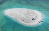 Photo diffusée le 21 mars 2024 par la Garde côtière philippine et le Bureau de la pêche et des ressources aquatiques (PCG/BFAR) montrant une vue aérienne de scientifiques philippins inspectant le récif de Sandy Cay, dans les îles Spratley, en mer de Chine méridionale