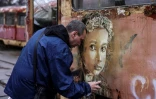 L'artiste français Christian Guémy, alias C215, peint l'une de ses oeuvres dans un quartier endommagé par une frappe russe à Kiev, le 1er avril 2022
