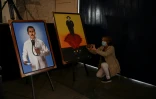 Une femme prend une photo de portraits du médecin vénézuélien Jose Gregorio Hernandez, installées dans la chapelle où a eu lieu sa béatification, à Caracas le 28 avril 2021