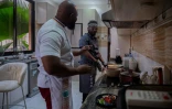 Le chef congolais Archi Dimosi parle avec son sous-chef lors de la préparation d'un plat dans sa cuisine, le 17 mai 2026 à Kinshasa, en RDC