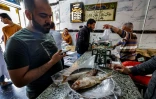 Des clients achètent du "fessikh", un plat traditionnel de poisson salé et fermenté, le 11 avril 2023 à Nabarouh, en Egypte