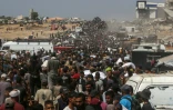 Des Palestiniens déplacés portant des sacs de vivres après une ruée sur des camions transportant de l'aide à Khan Younès, dans le sud de la bande de Gaza, le 9 août 2025