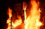Les portes d'un poste de police incendiées lors d'une manifestation à Rennes, dans l'ouest de la France, le 14 avril 2023 après la décision du Conseil consitutionnel de  valider l'essentiel de la réforme des retraites 