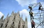 Des ouvriers préparent l'installation d'un écran géant qui doit retransmettre les funérailles de Silvio Berlusconi, le 13 juin 2023 devant la cathédrale de Milan